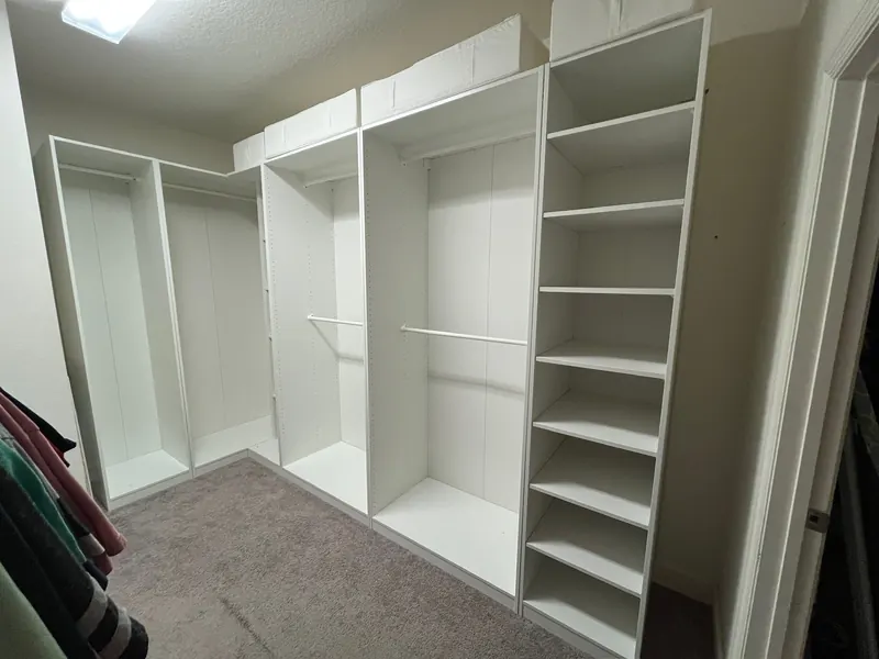 Walk-in closet with new white built-in shelving and hanging rods