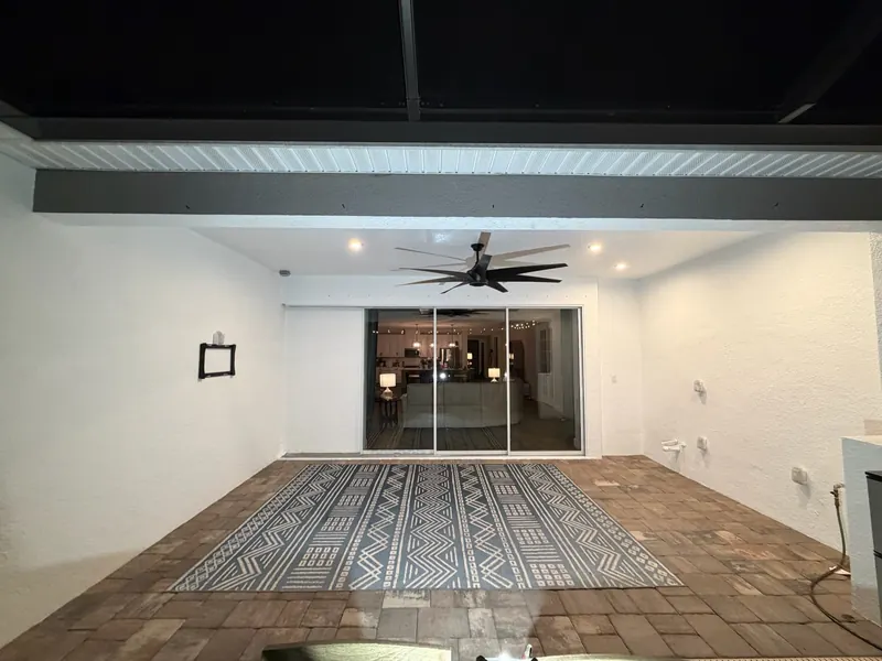 Screened lanai with fresh white walls, ceiling fan and paver floor