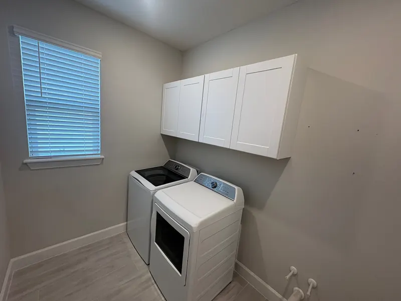 Laundry room with new white upper cabinets above washer and dryer