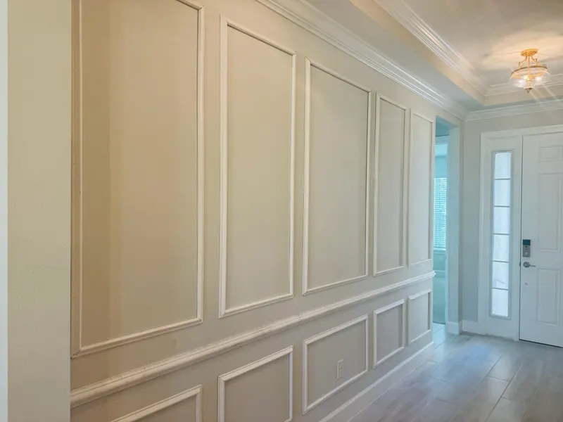 Entryway wall finished with white picture-frame wainscoting